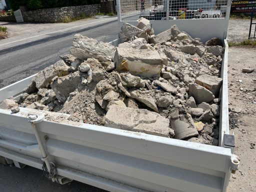 benne gravats Grosses pierres et débris de béton dans une benne près d'une route.